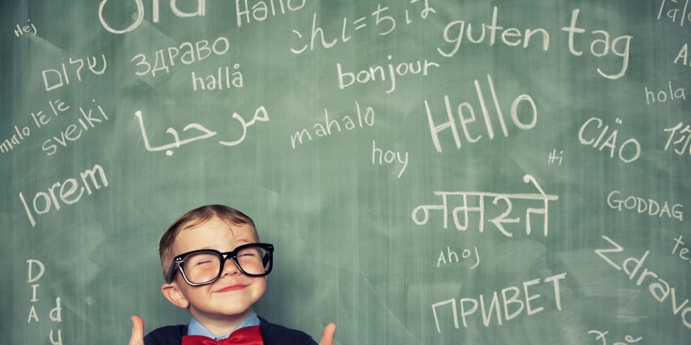 boy in front of chalk board with multiple languages written on it